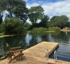Wooden jetty with a chair on a tree-lined lake